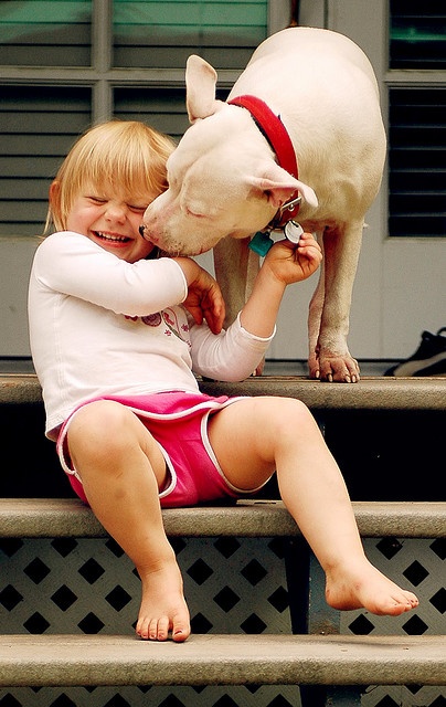 When in need of kisses, a kid can always count on her dog to give her some!