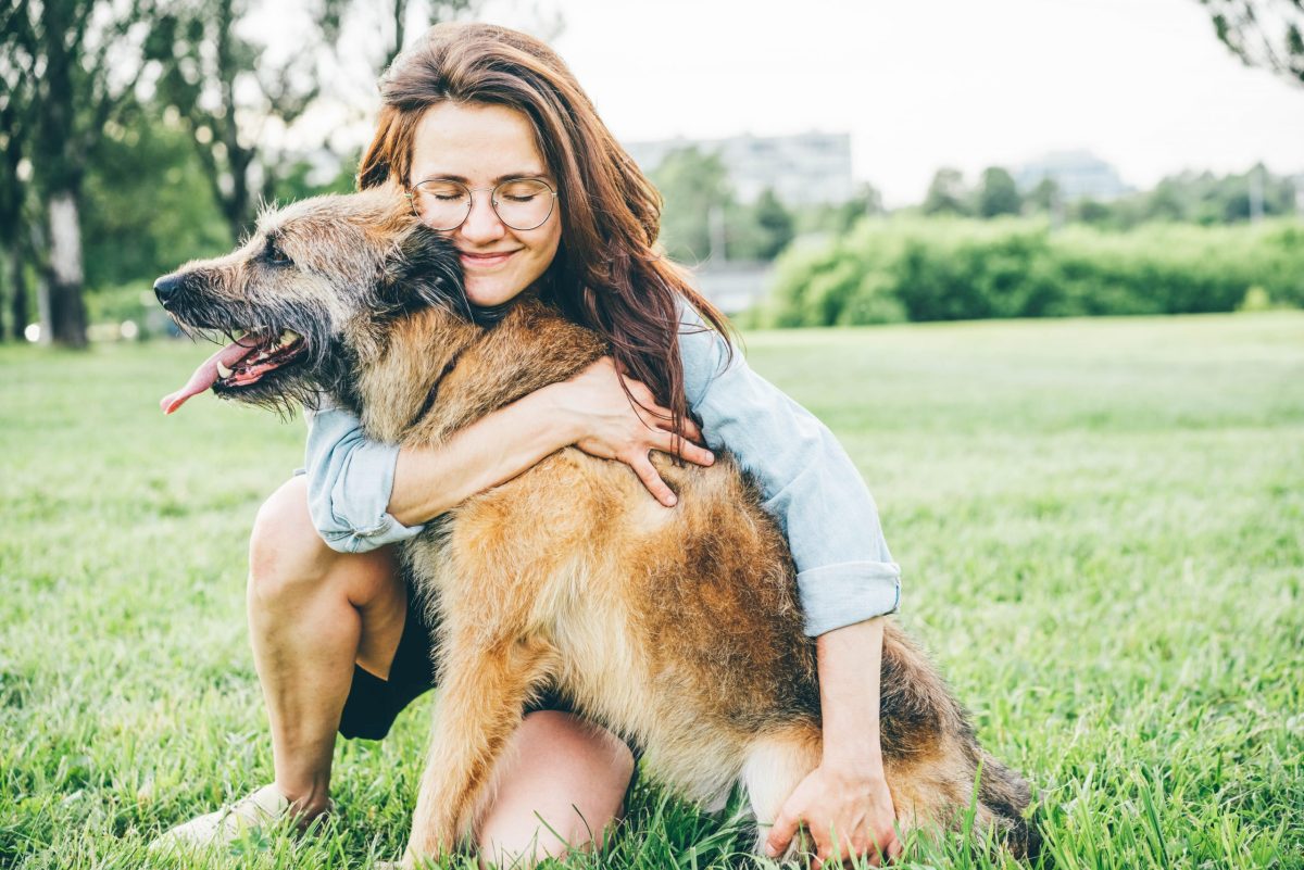 woman cuddling dog outside