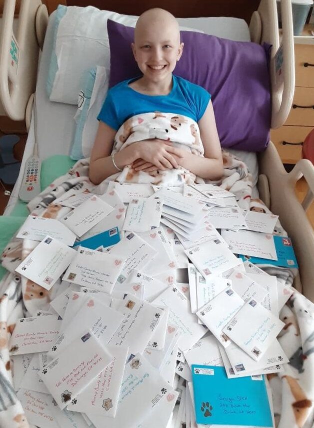 Avery in hospital bed with her cards