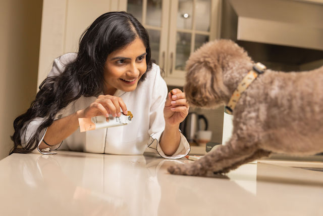 Woman feeding Monch bars to small dog