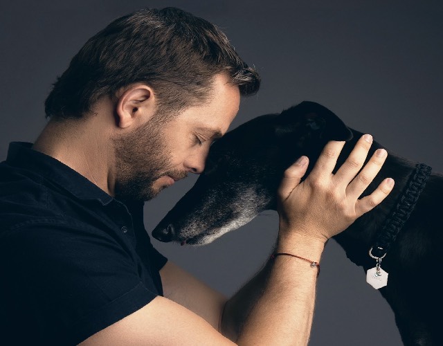 Man touching forehead of dog