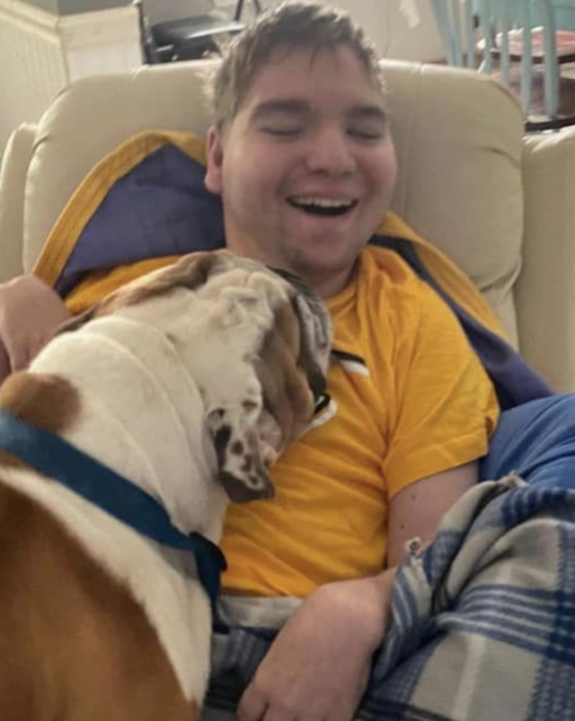 Bulldog kissing man with cerebral palsy