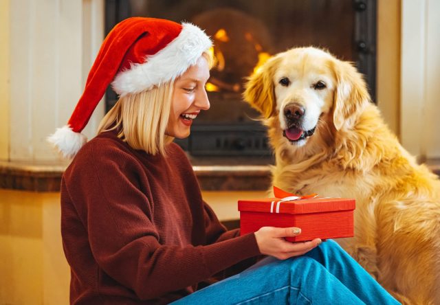 Woman and dog open Christmas gifts