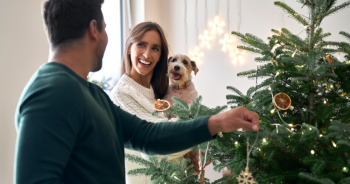 Woman holding dog by Christmas tree