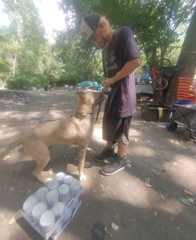 Homeless man giving dog food