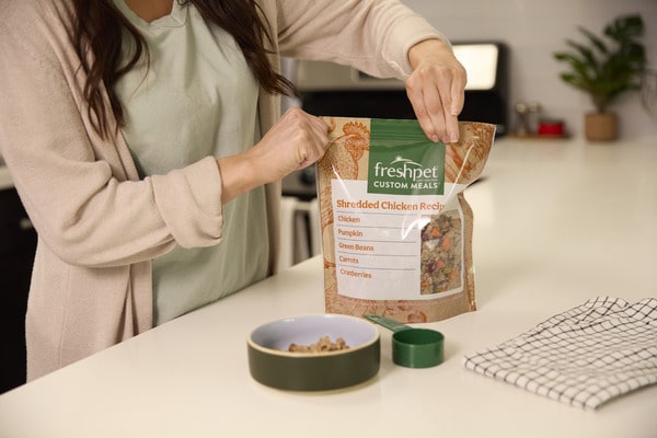 A woman preparing a bowl of Freshpet Custom Meals and sealing up bag