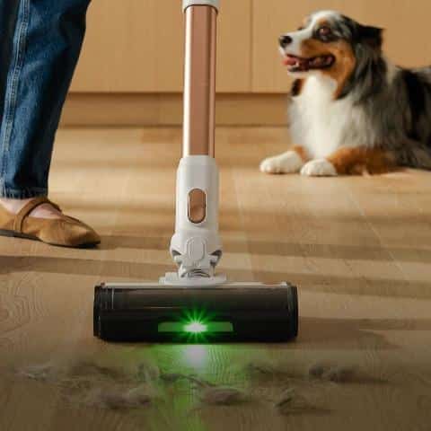 Green dust detection light illuminating tufts of shed pet hair on a hardwood floor