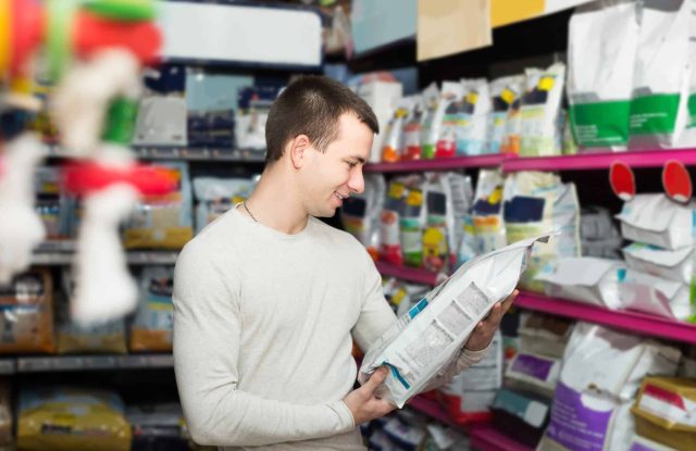 Dog owner reading the AAFCO nutritional adequacy statement on a dog food label