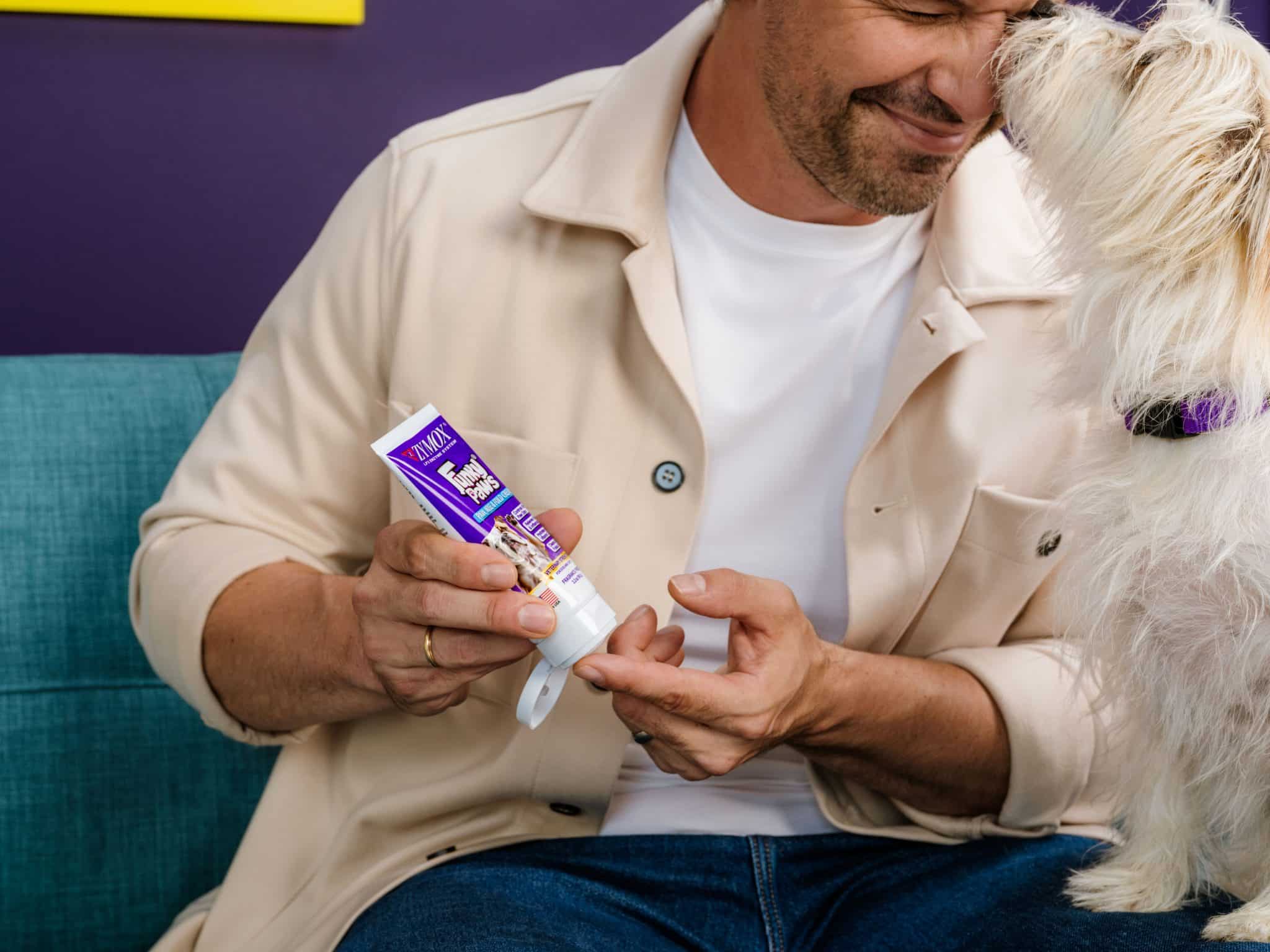 Man squeezing ZYMOX Funky Paws cream onto his fingertip